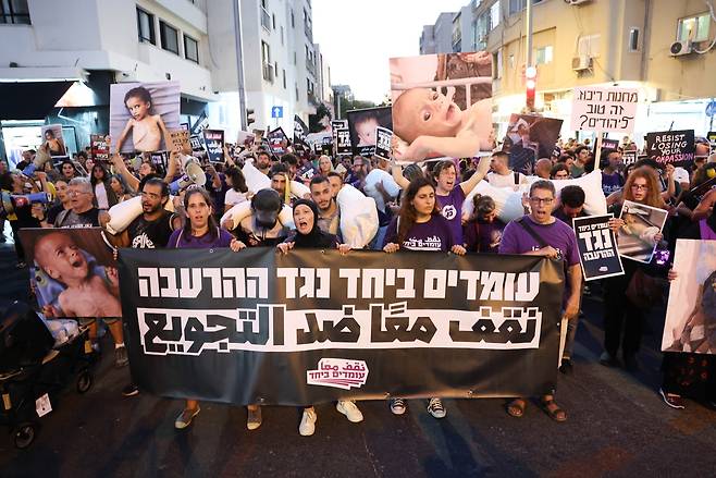이스라엘과 아랍계 활동가들이 지난 7월 22일(현지시간) 이스라엘 텔아비브에서 ‘굶주림에 맞서 함께 서자’라고 적힌 현수막과 팔레스타인 가자지구 아이들의 사진, 밀가루 자루를 들고 행진하고 있다. EPA연합뉴스