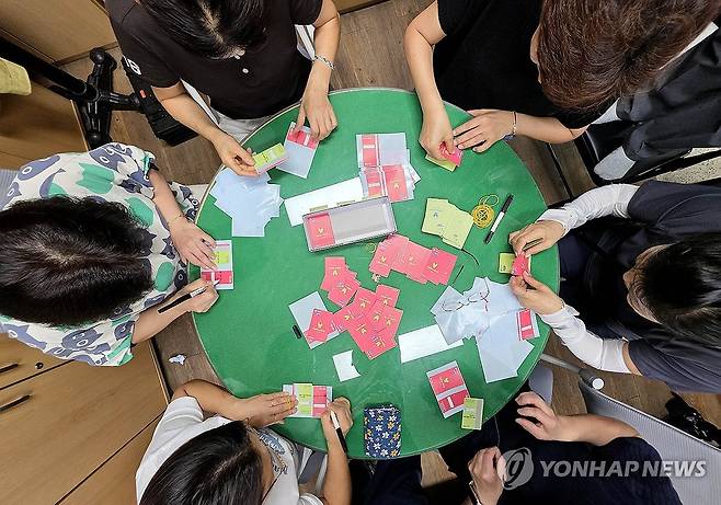 '색깔 차별 논란' 소비쿠폰 색상 교체 (광주=연합뉴스) 24일 광주 북구 용봉동 행정복지센터에서 직원과 통장들이 민생회복 소비쿠폰 현물카드에 스티커를 붙여 색상을 교체하고 있다. 광주시는 소득 수준별 소비 쿠폰 현물 카드 색상을 달리해 물의를 빚었다가 한가지 색상으로 교체하기로 했다. 2025.7.24 [광주 북구 제공. 재판매 및 DB 금지] in@yna.co.kr