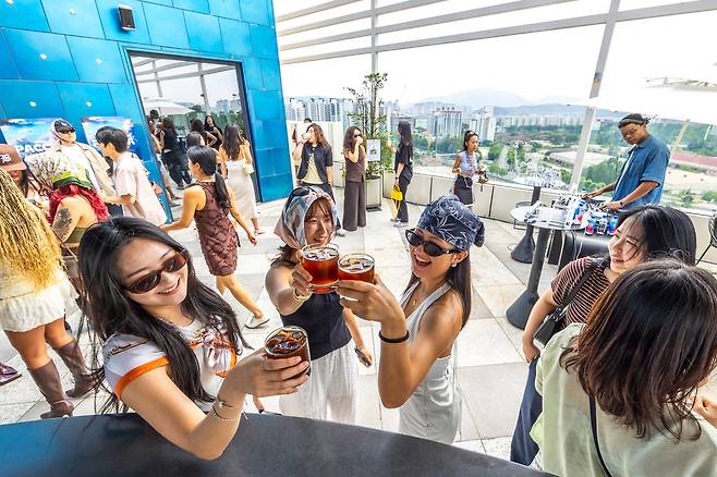 People dance with iced Americanos in hand alongside a DJ during a coffee rave on the rooftop of a hotel in Seoul’s Itaewon neighborhood on July 5, 2025./Lee Shin-young