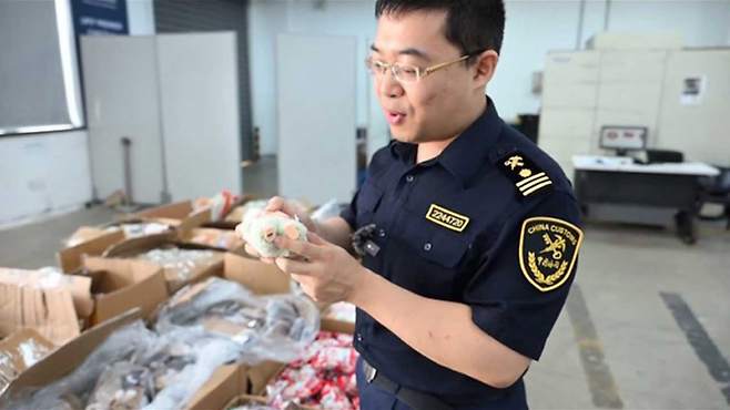 인형발바닥 보며 설명하는 세관원