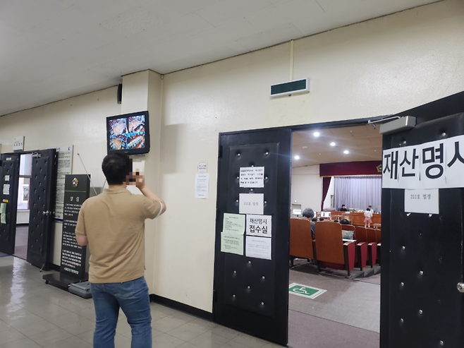 16일 오전 서울중앙지방법원 4별관에서 경매가 진행 중인 모습. 한 시민이 법정 모니터를 보며 통화를 하고 있다. [사진=위지혜 기자]