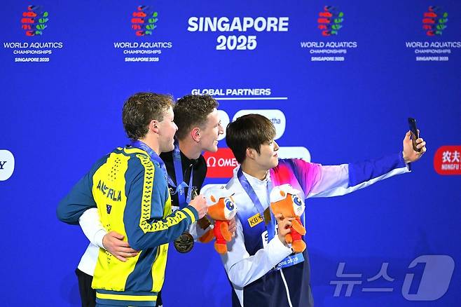 김민(오른쪽)이 27일 열린 2025 싱가포르 세계수영선수권대회 남자 자유형 400m 결선에서 3분42초60의 기록으로 동메달을 획득했다. 시상대에 오른 김우민이 루카스 메르텐스(가운데), 새무얼 쇼트(왼쪽)와 함께 기념사진을 촬영하고 있다다. ⓒ AFP=뉴스1