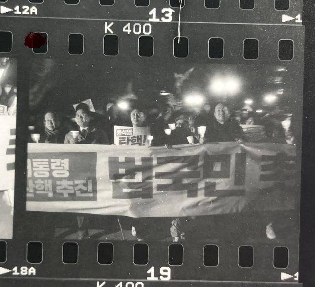 '미공개 컷' 이재명 대통령(당시 더불어민주당 대표, 왼쪽 첫 번째)이 사진가를 똑바로 쳐다보는 사진. 사진가에 따르면, 당시 이 대표의 표정에서 "너 도대체 누구야?"라는 듯한 느낌을 받았다고. 결국 전시회에는 이 사진을 사용하지 않았지만, <더팩트>에 스캔 전 필름 상태 그대로 사진을 처음으로 공개했다. /폴 개드 사진가 제공