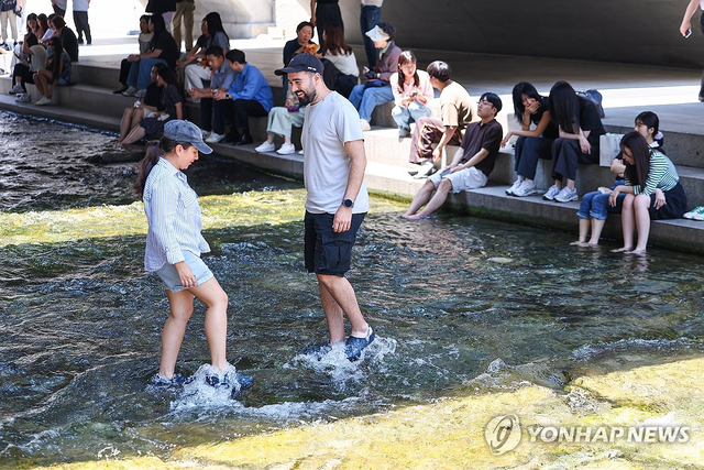 서울시가 청계천 복원 20주년 맞아 상류 구간 개방한 가운데 외국인 관광객이 발을 담그며 휴식을 취하고 있다. 연합뉴스