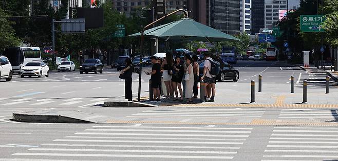 최고 체감온도가 35도 안팎으로 오르며 전국이 매우 무더운 날씨를 보인 27일 오후 서울 종로구 광화문의 건널목 그늘막 아래에 시민들이 옹기종기 모여 햇빛을 피하고 있다. 김혜윤 기자 unique@hani.co.kr