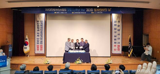 26일 서울 광진구 건국대병원 대강당에서 열린 대한방사선사협회 창립 60주년 기념 행사에서 한정환(가운데) 회장을 비롯한 협회 임원진이 기념 떡을 썰고 있다. 이들은 무대 양옆 현수막에 대정부 요구사항을 명시했다. /사진=정심교 기자