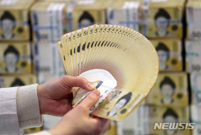 [서울=뉴시스] 고승민 기자 = 한국은행이 미국 연방준비제도이사회(Fed·연준)와의?600억달러 규모의 통화스와프 계약을 6개월 재연장했다고 밝힌 17일 서울 중구 하나은행에서 관계자가 원화를 들어 보이고 있다. 통화스와프는 미리 정한 환율에 따라 필요한 만큼의 돈을 상대국 통화와 교환할 수 있도록 한 계약으로 일종의 '마이너스 통장' 개념이다. 언제든 달러를 꺼내 쓸 수 있다는 점에서 경제·금융위기시 안전판 역할을 한다. 2020.12.17. kkssmm99@newsis.com