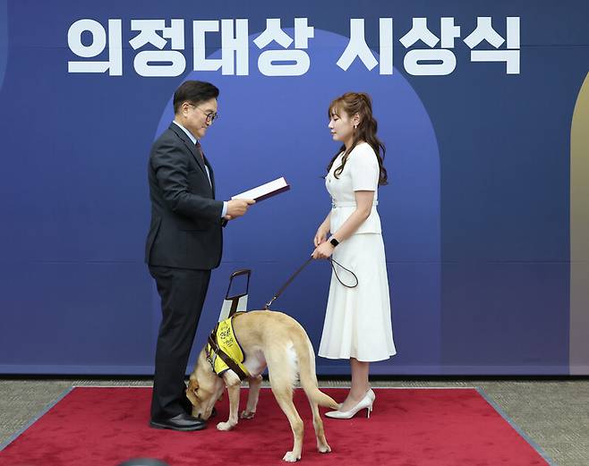 국민의힘 김예지 의원이 지난달 11일 서울 여의도 국회에서 열린 제5회 대한민국 국회 의정대상 시상식에서 우원식 국회의장으로부터 우수입법의원 의정대상을 받고 있다. 가운데는 김 의원의 안내견인 태백이. 연합뉴스