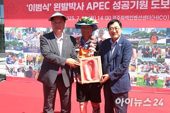 28일 경주화백컨벤션센터(HICO) 행사장에서 이범식(중앙) 박사가 왼발 완주 기념 풋프린팅 상패를 전달받고 주낙영(오른쪽) 경주시장, 이동협 경주시의회 의장과 함께 기념촬영을 하고 있다. [사진=경주시청]