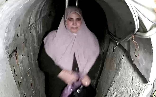[뉴시스] 팔레스타인 무장정파 하마스 최고 지도자 야히야 신와르의 부인인 사마르 무하마드 아부 자마르가 명품 가방을 들고 하마스 터널을 통해 탈출하는 모습. (사진=이스라엘군) 2025.7.28 *재판매 및 DB 금지