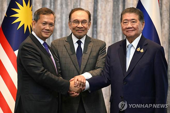 태국-캄보디아 전격 휴전 합의 28일(현지시간) 말레이시아 쿠알라룸푸르에서 훈 마네트 캄보디아 총리(사진 왼쪽)와 태국 총리 권한대행인 품탐 웨차야차이 부총리 겸 내무부 장관(오른쪽)이 휴전에 합의한 뒤 회담을 중재한 안와르 이브라힘 말레이시아 총리(가운데)와 함께 손을 잡고 있다. [AP 연합뉴스. 재판매 및 DB 금지]