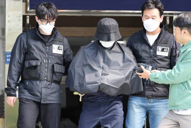 부산 법원 앞에서 생방송하던 유튜버를 살해한 혐의(특가법상 보복살인)를 받는 50대 유튜버가 지난해 5월 16일 오전 부산 연제경찰서에서 검찰 송치를 위해 이동하고 있다. 연합뉴스