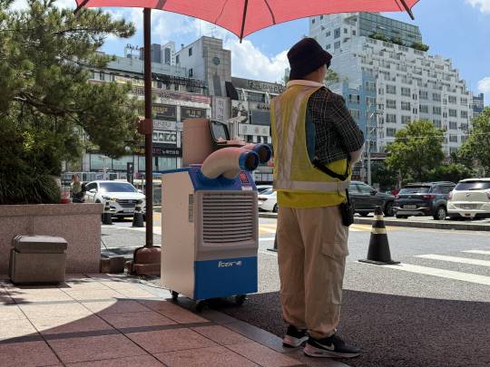 29일 대전 한 유통매장 주차 안내 요원이 파라솔 밑에서 햇빝을 피하고 있다.