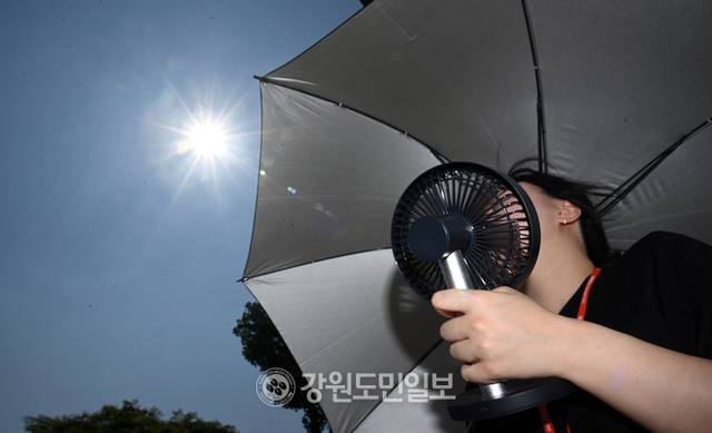 ▲ 계속되는 폭염에 전국이 펄펄 끓고 있는 가운데 29일 춘천 요선동에서 한 시민이 양산과 손 선풍기로 더위를 식히고 있다. 방도겸 기자