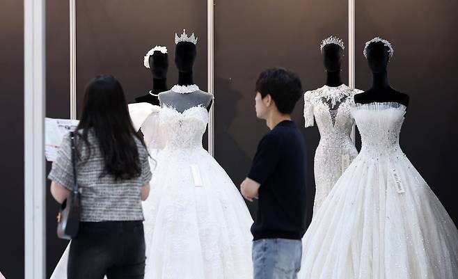 서울 강남구에서 열린 한 웨딩 박람회에서 전시된 드레스를 살펴보는 예비 부부. 사진=뉴스1