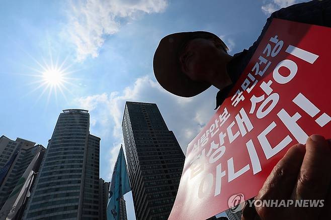생존을 위해 마주한 도심의 불볕 (서울=연합뉴스) 서대연 기자 = 서울 한낮 기온이 36도까지 치솟으며 무더운 날씨를 보인 28일 서울 용산구 삼각지역 인근에서 열린 한미 상호관세 협상 농축산물 개방 반대 결의대회에서 한 참가자가 팻말을 들고 있다. 2025.7.28 dwise@yna.co.kr