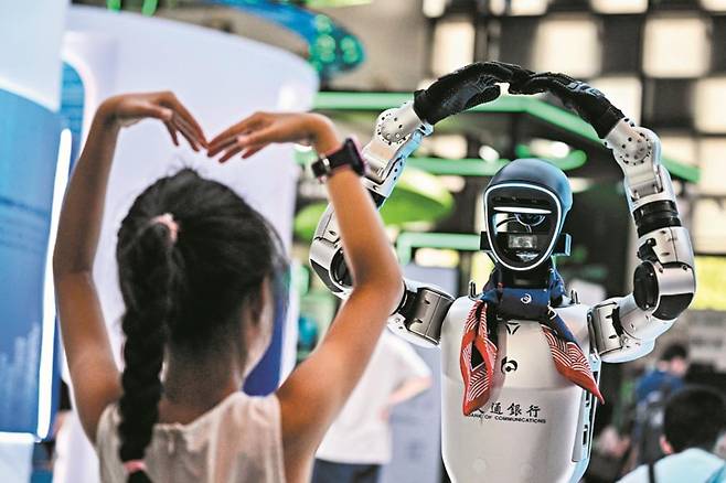 중국 기업들이 AI 시장을 빠르게 장악하고 있다. 지난 26~28일 중국 상하이에서 열린 세계인공지능대회(WAIC)에서도 중국은 뛰어난 성능의 AI 신제품을 대거 선보였다. 사진은 28일 WAIC에서 한 소녀 관람객이 춤추는 AI 로봇을 따라 하는 모습./AFP 연합뉴스