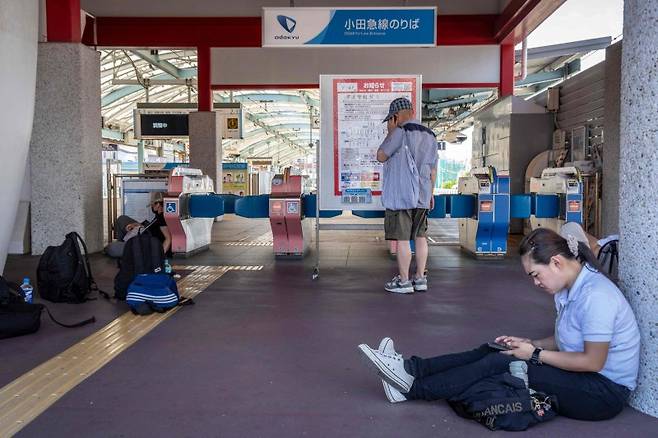 30일 일본 가나가와현 후지사와시의 가타세에노시마역에서 시민들이 지진해일(쓰나미) 경보로 폐쇄된 역사에 들어가지 못해 기다리고 있다.AFP연합뉴스