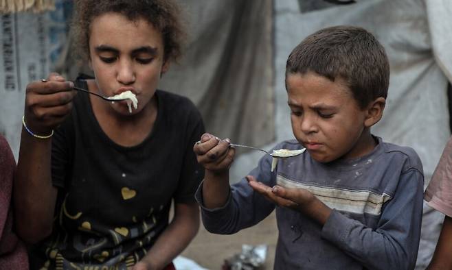 29일(현지시각) 다섯 아이의 아버지인 모하메드 아부 암샤(39)의 자녀들이 가자 북부 가자시티 텐트 안에서 음식을 먹고 있다. 가족들은 식량 배급으로 얻은 극소량의 밀가루만을 먹고 있었다. 가자시티/신화 연합뉴스
