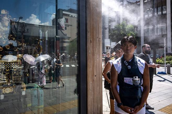 지난 28일 일본 도쿄 쇼핑가 근처에서 더위를 식히기 위해 인공 안개 아래에 서 있는 사람들. 사진=AFP(연합뉴스)