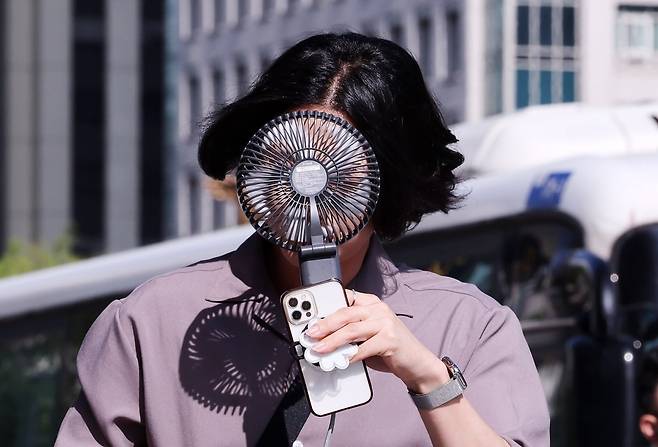 서울 종로구 광화문광장 인근에서 한 시민이 손선풍기를 얼굴에 대며 출근하고 있다./ 사진=뉴스1