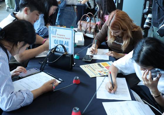 Foreign students write their resumes at a job fair in Busan on Sept. 27, 2024. [YONHAP]