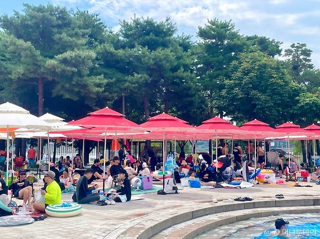 30일 오전 서울 광진구 뚝섬한강공원 수영장에서 시민들이 파라솔 아래 더위를 식히고 있다./사진=이현수 기자.