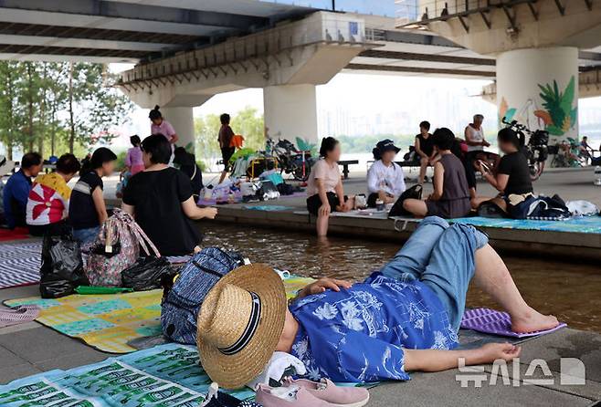 [서울=뉴시스] 이영환 기자 = 서울의 낮기온이 37도까지 오르며 폭염이 지속되고 있는 29일 오후 서울 영등포구 마포대교 남단에서 시민들이 휴식을 취하고 있다. 2025.07.29. 20hwan@newsis.com