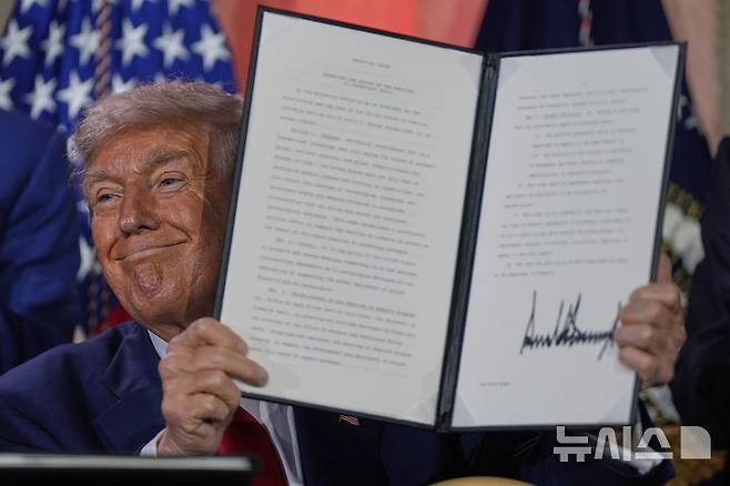 [워싱턴=AP/뉴시스] 도널드 트럼프 미국 대통령이 23일(현지 시간) 워싱턴의 앤드루 W. 멜론 강당에서 열린 AI 정상회의에 참석해 연설한 뒤 서명한 AI 관련 행정명령을 들어 보이고 있다. 2025.07.24.