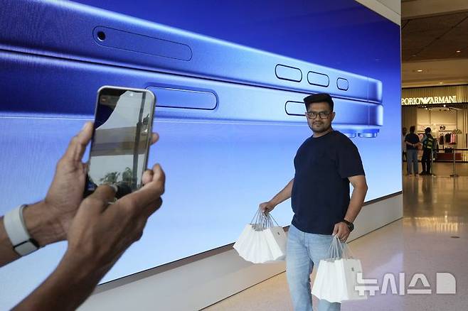 [뭄바이=AP/뉴시스] 20일(현지시각) 인도 뭄바이의 아이폰16 스마트폰 판매 첫날 한 고객이 애플 매장에서 아이폰16을 구매한 후 기념사진을 찍고 있다. 2024.09.20.