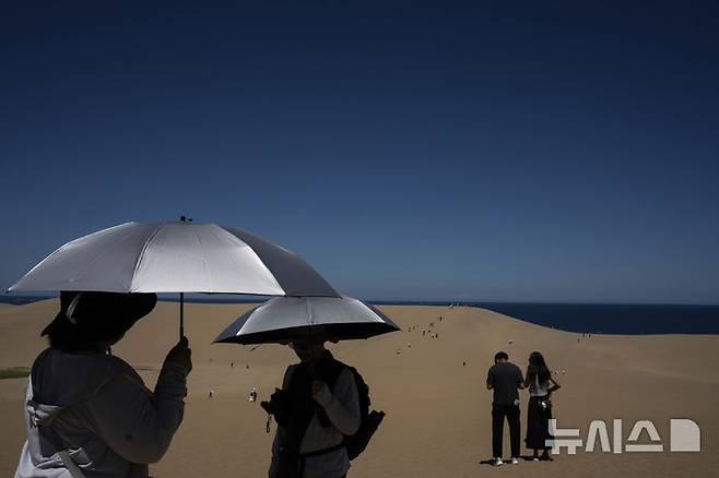 [돗토리(일본)=AP/뉴시스]일본 돗토리(鳥取)현의 돗토리 사구 관광에 나선 관광객들이 28일 뜨거운 햇볕을 가리기 위해 파라솔을 펼쳐들고 있다. 30일 오후 2시39분 일본 효고(兵庫)현 단바( 丹波) 기온이 41.2도를 기록, 일본 사상 최고 기록을 경신했다고 NHK가 보도했다. 다른 곳들에서도 40도를 넘는 더위로 생명을 위협하는 폭염이 나타나 열사병에 대한 경계를 높이고 있다. 2025.07.30.