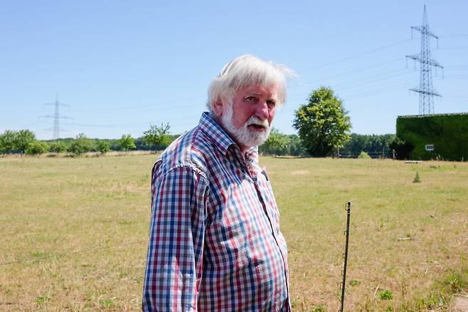 초고압 송전망 건설에 반대해 10년 넘게 법정 싸움을 벌인 린드너 씨가 집 주변 송전탑 앞에 섰다. ⓒ기후시민프로젝트 제공