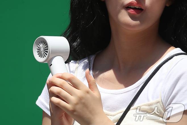 폭염이 계속된 1일 대구 중구 동성로에서 한 시민이 휴대용 선풍기 바람을 맞으며 발걸음을 옮기고 있다. 2025.8.1/뉴스1 ⓒ News1 공정식 기자