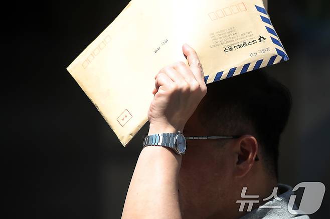 폭염이 계속된 1일 대구 중구 동성로에서 한 시민이 서류 봉투로 뙤약볕을 가린 채 발걸음을 옮기고 있다. 2025.8.1/뉴스1 ⓒ News1 공정식 기자