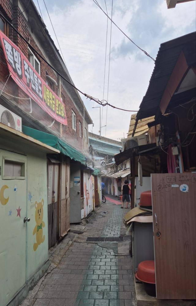 지난달 30일 서울 영등포구 영등포 쪽방촌 한 골목에 쿨링포그(물안개분사장치)가 뿌려지고 있는 가운데, 주민들이 야외로 나와 더위를 식히고 있다. 이재명 기자