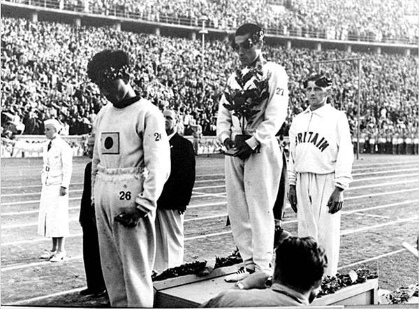 1936년 베를린올림픽대회에서 일장기를 달고 출전해 마라톤 금메달을 딴 손기정 선수와 3위(동메달)에 입상한 남승룡 선수가 시상식에 올랐다. 손기정(27번)은 금메달리스트에만 주어지는 월계수 화분으로 가슴에 새겨진 일장기를 가렸지만, 화분이 주어지지 않은 남승룡(26번) 선수는 고개를 숙이고 있다.  [조직위원회 제공]