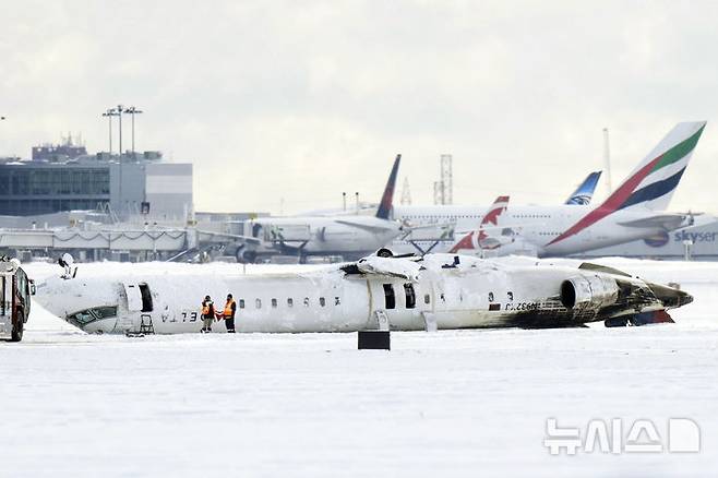 [토론토=AP/뉴시스] 2월 18일 캐나다 토론토 피어슨 공항 활주로에서 델타항공 소속 항공기가 뒤집힌 채 놓여 있다. 전날 발생한 델타항공 여객기 전복 사고에도 탑승객 80명 전원이 무사했다. 2025.08.01.