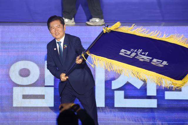 더불어민주당 정청래 신임 당대표가 2일 고양 킨텍스에서 열린 전국당원대회에서 김병기 당대표 직무대행 겸 원내대표로부터 받은 당기를 흔들고 있다. 연합뉴스