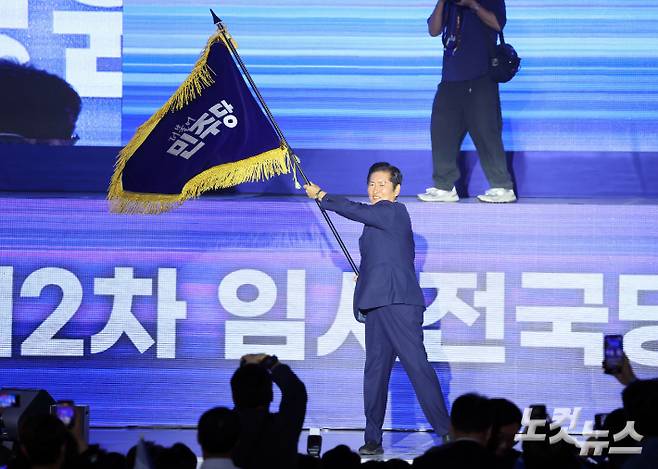 더불어민주당 정청래 신임 당대표가 2일 오후 2일 오후 경기 고양시 킨텍스에서 열린 제2차 임시전국당원대회에서 당기를 흔들고 있다. 황진환 기자