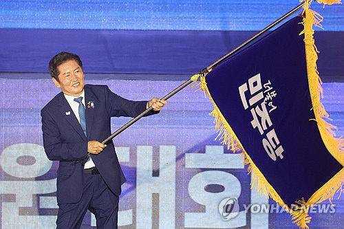 더불어민주당 정청래 신임 당대표가 2일 고양 킨텍스에서 열린 전국당원대회에서 김병기 당대표 직무대행 겸 원내대표로부터 받은 당기를 흔들고 있다.