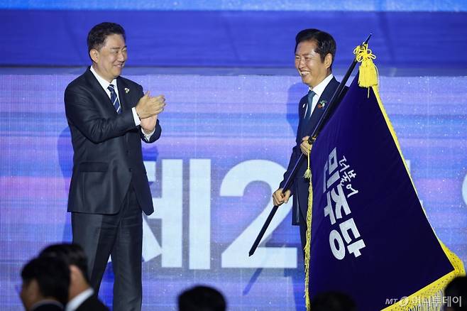 [고양=뉴시스] 고승민 기자 = 정청래 더불어민주당 신임 당대표가 2일 경기 고양시 킨텍스에서 열린 제2차 임시전국당원대회에서 김병기 원내대표로 부터 당기를 이양받고 있다. (공동취재) 2025.08.02. photo@newsis.com /사진=고승민