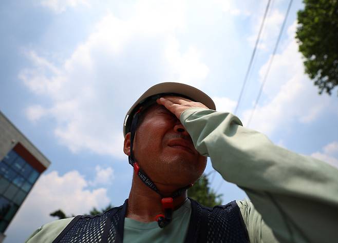 2025년 7월29일 서울 종로구 국정기획위원회 앞에서 열린 민주노총 건설노조 폭염 실태 기자회견에서 한 참가자가 얼굴에 맺힌 땀을 닦고 있다. 연합뉴스