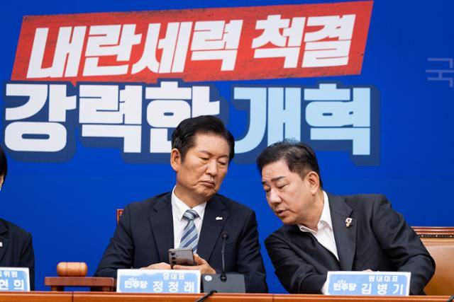 정청래(왼쪽) 더불어민주당 대표와 김병기 원내대표가 4일 서울 여의도 국회에서 열린 최고위원회의에서 대화하고 있다. 이들 뒤 벽면에 '내란세력 척결, 강력한 개혁'이라 적힌 새 뒷걸개가 걸려 있다. 뉴스1