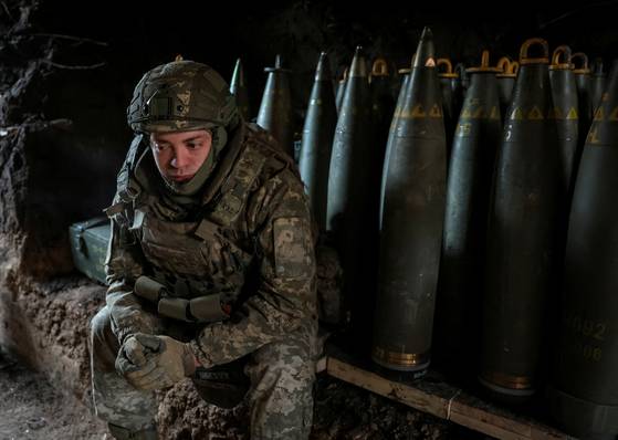 올해 2월 8일 우크라이나 도네츠크 지역에서 한 우크라이나 군인이 발사 명령을 기다리는 동안 포탄 근처에 앉아 있다. 로이터=연합뉴스