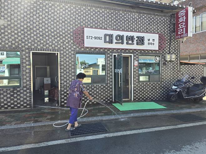 1일 대의반점 배영자 사장이 가게 앞 물을 뿌리며 장사 개시를 준비하고 있다