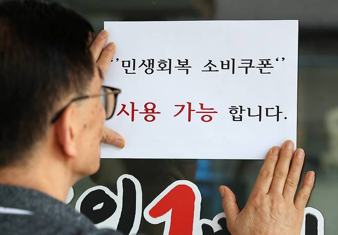 대구 중구의 한 음식점 주인이 출입문에 민생회복 소비쿠폰 사용 가능 안내문을 붙이고 있다./뉴스1
