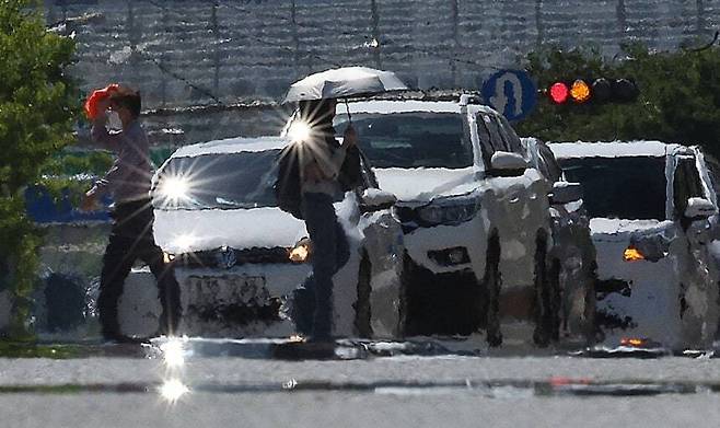 지난달 22일 북태평양고기압이 우리나라를 덮은 가운데, 폭염경보가 발령된 대구 달서구 계명대학교 인근 도로에서 시민들이 양산과 옷가지 등으로 햇볕을 막으며 이동하고 있다. 연합뉴스