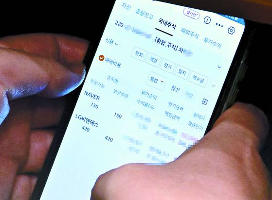 A photo published by The Fact shows Lee Choon-suak, a Democratic Party lawmaker and chair of the National Assembly’s Legislation and Judiciary Committee, checking a trading account registered under an aide's name during a plenary session on Aug. 4. [THE FACT]