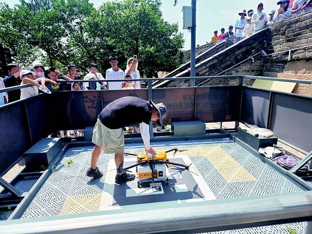 지난 1일 중국 베이징 외곽에 위치한 만리장성 바다링 난우청루에서 메이퇀 드론 배송 관리자가 드론으로 배송된 음식을 꺼내기 위해 드론을 조작하고 있다. 그는 최근 하루에 70∼100건 정도의 드론 배송이 이뤄진다고 말했다.