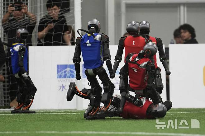 [베이징=AP/뉴시스] 4일(현지 시간) 중국 베이징에서 '2025 세계 휴머노이드 로봇 게임'을 앞두고 언론 공개 행사가 열린 가운데 부스터 휴머노이드 로봇들이 축구 시범 경기로 기술을 선보이고 있다. 오는 14일부터 17일까지 열리는 이 행사에는 축구를 비롯해 달리기, 격투, 댄스 등 실제 사람의 경기와 유사한 종목이 포함된 것으로 알려졌다. 2025.08.04.